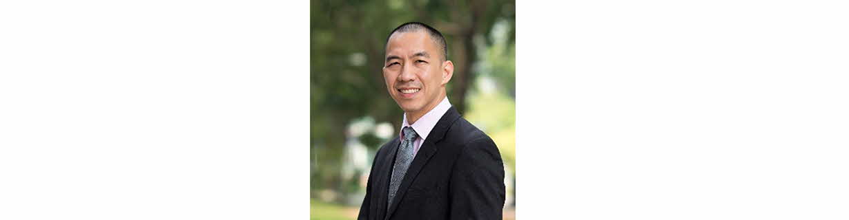 Portrait of Lien Choon Luen, man in a business suit with a buzzcut crop, smiling